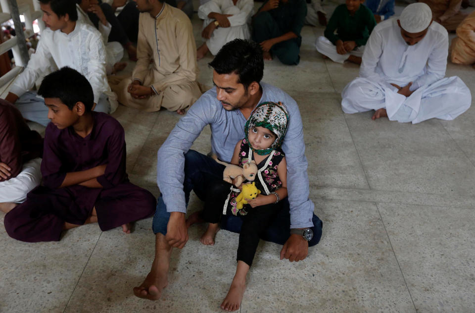 A girl holds her stuffed toys as she sits with her father as they listen to sermon with others before Friday prayers at a mosque during a Muslim holy month of Ramadan in Karachi, Pakistan June 16, 2017. REUTERS/Akhtar Soomro