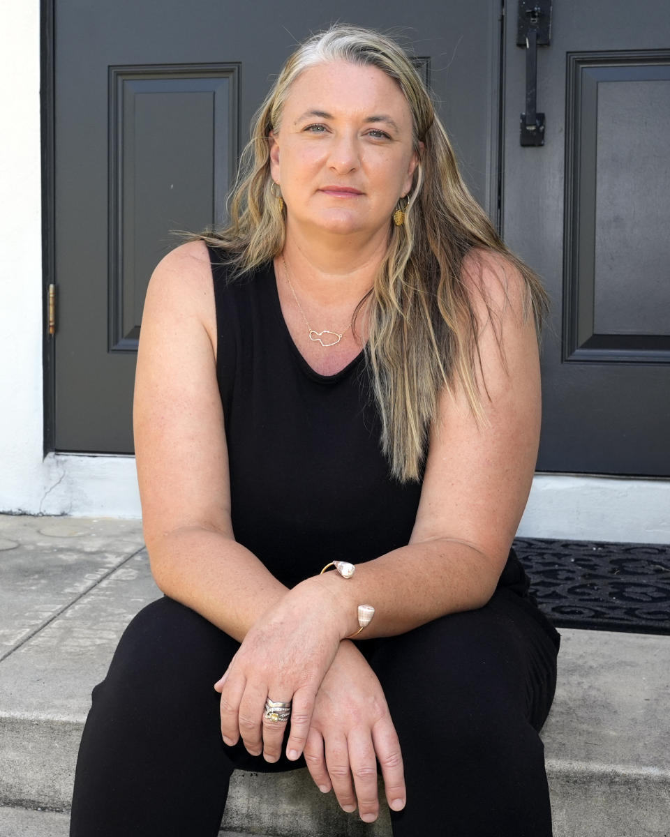 Amy Chadwick poses her current home Monday, April 8, 2024, in Satellite Beach, Fla. Chadwick, a victim of the fires in Hawaii moved to Florida where she could stretch her homeowners insurance dollars while she waits for her lot to be cleared and for permission to rebuild. (AP Photo/John Raoux)