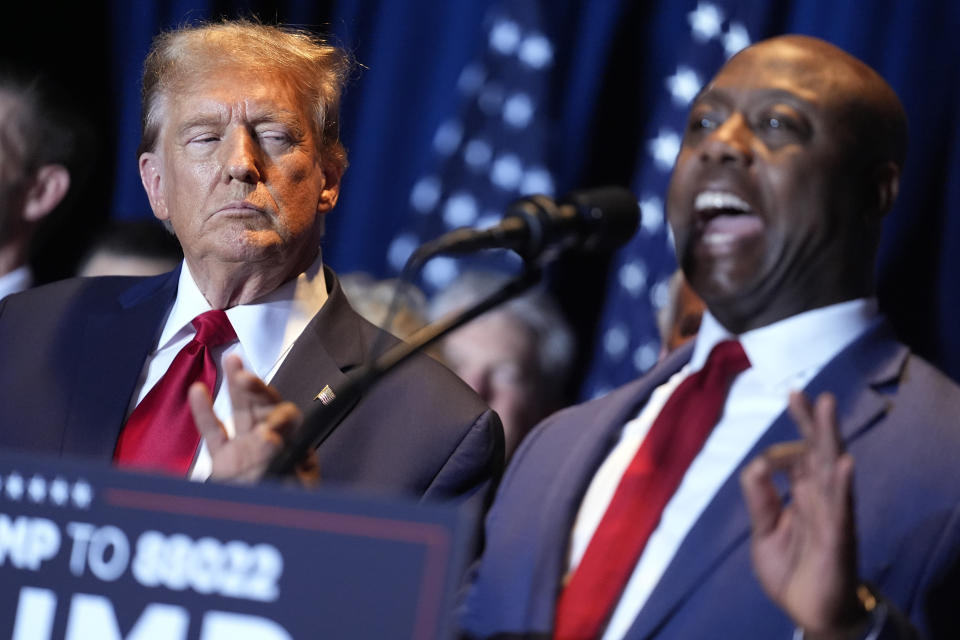 Republican presidential candidate former President Donald Trump listens as Sen. Tim Scott, R-S.C., speaks at a primary election night party at the South Carolina State Fairgrounds in Columbia, S.C., Saturday, Feb. 24, 2024. (AP Photo/Andrew Harnik)