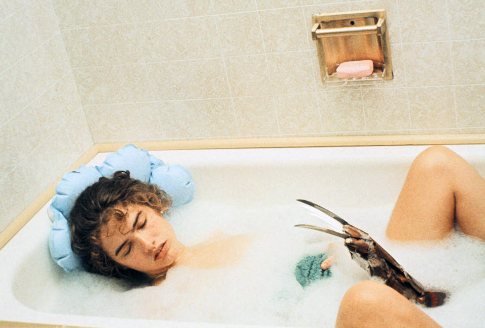 Heather Langenkamp asleep in a bubble bath with Freddy Krueger's claw coming up from the water