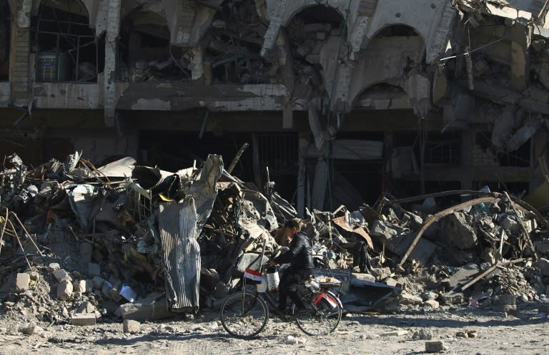 An Iraqi boy rides his bicycle past destruction in in the Old City of Mosul, where Iraqi forces declared victory against the Islamic State group after months of fighting that killed hundreds of civilians