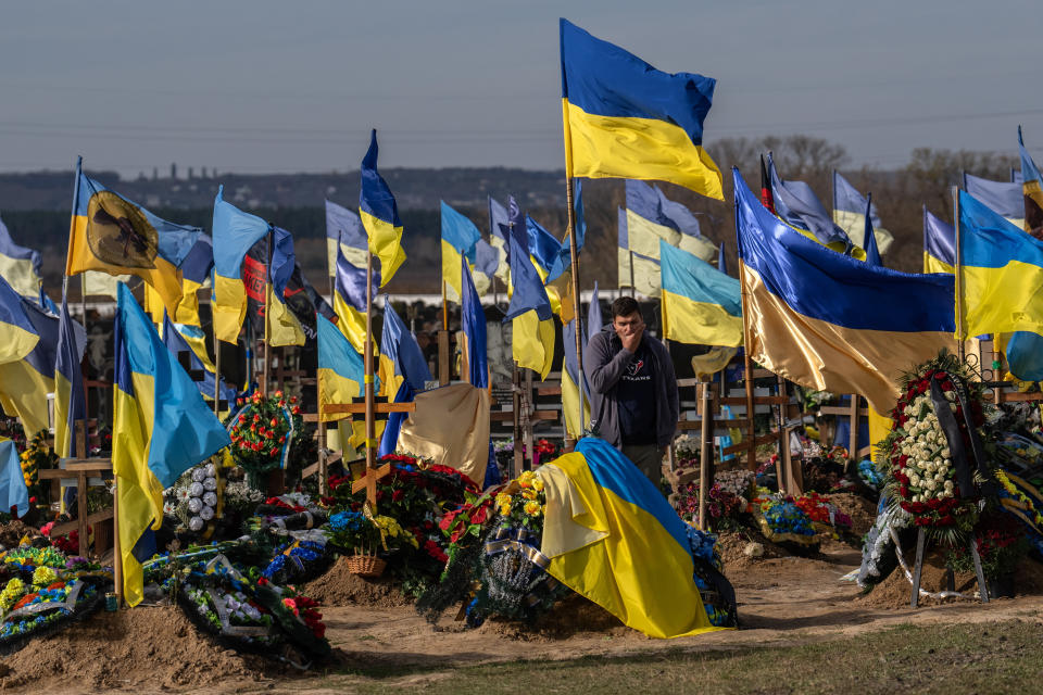 KHARKIV, UKRAINE - OCTOBER 19: A man pauses by a grave as Ukrainian flags fly in a cemetery for soldiers killed in action following the Russian invasion earlier this year, on October 19, 2022 in Kharkiv, Ukraine. Russia's president Vladimir Putin today imposed martial law on the four Ukrainian regions occupied by Russian forces as large numbers of civilians were being moved out of the Kherson area ahead of a Ukrainian offensive. (Photo by Carl Court/Getty Images)