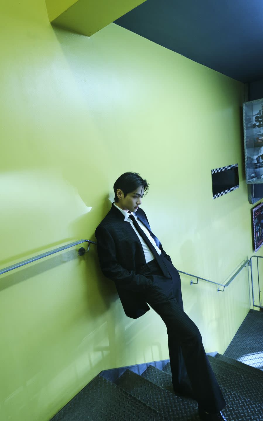a person in a suit leaning against a wall