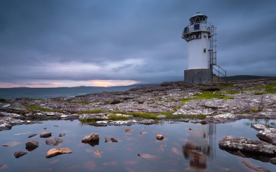 A lighthouse looks over a limpid Loch Broom - Credit: GETTY
