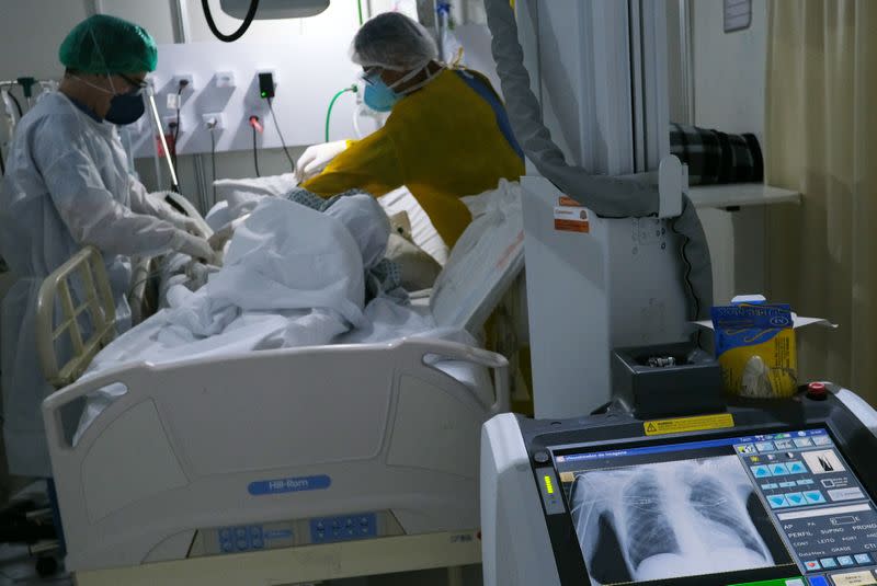 Trabajadores de la salud examinan a una persona enferma con COVID-19 en el hospital de campaña Lagoa-Barra, en Río de Janeiro, Brasil