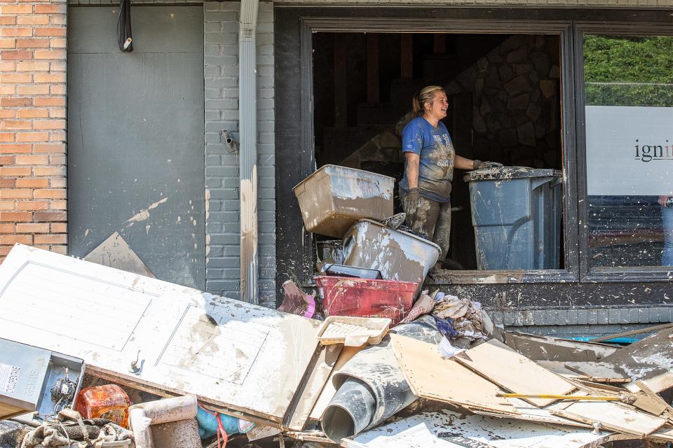 Mistie Johnson, pastor at Ignite Church in Neon, Kentucky laughs with volunteers while cleaning mud and debris from her church on Saturday July 30, 2022