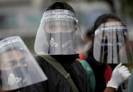 Activists wearing protective face shields as a precaution against the new coronavirus outbreak attend a small protest outside the parliament in Jakarta, Indonesia, Tuesday, July 14, 2020. About a dozen activists staged the protest opposing the government's omnibus bill on job creation that was intended to boost economic growth and create jobs, saying that it undermined labor rights and environmental protection. (AP Photo/Dita Alangkara)