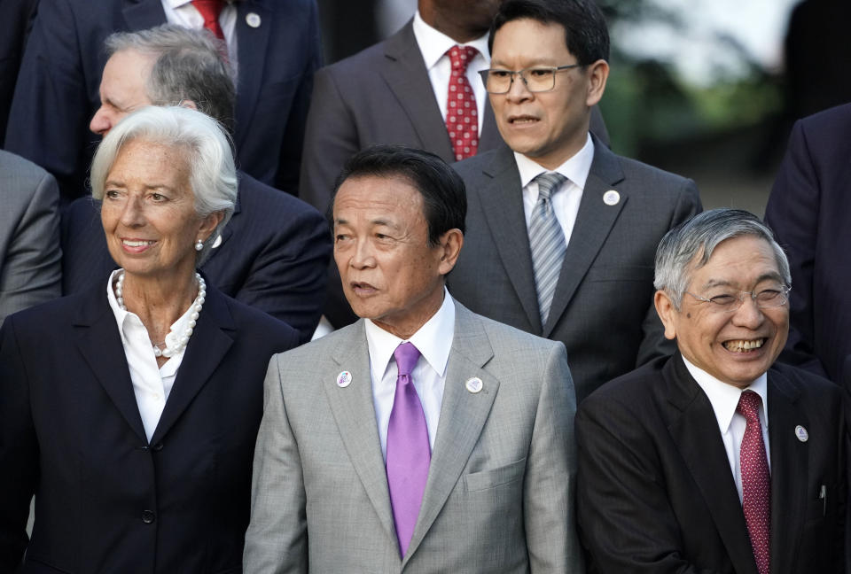 Japan's Finance Minister Taro Aso, center, stands with IMF Managing Director Christine Lagarde, left, and Bank of Japan Governor Haruhiko Kuroda, right, before a family photo of the G20 finance ministers and central bank governors meeting Saturday, June 8, 2019, in Fukuoka, Japan. The G20 finance ministers and central bank governors meeting is taking place in Fukuoka June 8-9. (Franck Robichon/Pool Photo via AP)