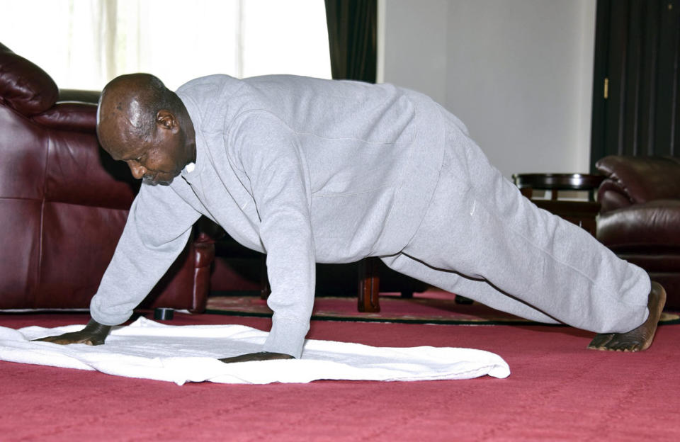 In this handout photo provided by Uganda's Presidential Press Unit, Uganda's President Yoweri Museveni performs push-ups in a video released to the public via the president's social media accounts, at State House in Entebbe, Uganda Thursday, April 9, 2020. Uganda's 75-year-old president has released a homemade exercise video to show skeptical countrymen that one can stay in shape under the lockdown that has been implemented to curb transmission of the new coronavirus. (Uganda Presidential Press Unit via AP)