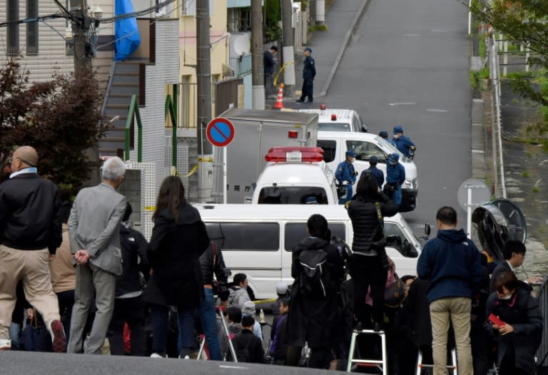 Journalists gather in front of an apartment (partially covered with a blue sheet) where the headless bodies were found