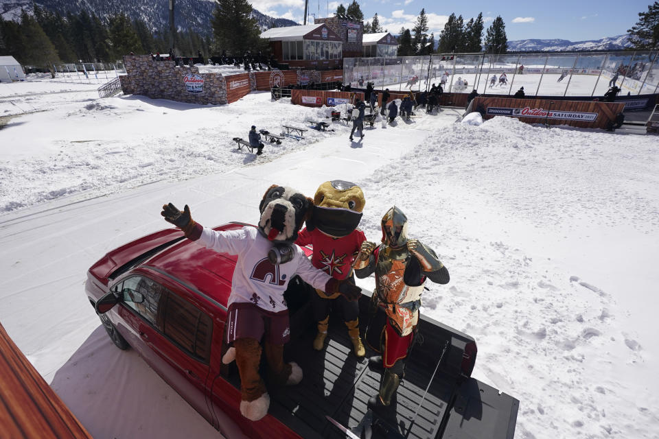 Bernie, the St. Bernard, left, the mascot of the Colorado Avalanche poses for photos with Vegas Golden Knights mascots, Chance, the Gila monster, center, and the Golden Knight, right, before the start of the Outdoor Lake Tahoe NHL hockey game between the two teams at Stateline, Nev., Saturday, Feb. 20, 2021. (AP Photo/Rich Pedroncelli))