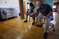 Arthur Graham, prosthetist at Next Step Bionics & Prosthetics, right, checks the fit of Claudine Humure's prosthetic leg, Monday, Sept. 20, 2021, in Newton, Mass. Humure, of Rwanda, was orphaned during her country's genocide and lost part of her leg to childhood cancer. Her new leg was provided free by the prosthetic clinic and features the latest in artificial limb technology. (AP Photo/Charles Krupa)