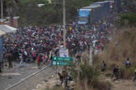 Honduran migrants, top, stand between cargo trucks as they confront Guatemalan soldiers and police blocking them from advancing toward the US, on the highway in Vado Hondo, Guatemala, Monday, Jan. 18, 2021. The roadblock was strategically placed at a chokepoint on the two-lane highway flanked by a tall mountainside and a wall leaving the migrants with few options. (AP Photo/Sandra Sebastian)