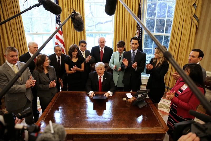 President Trump signs an executive order cutting regulations, accompanied by small business leaders at the Oval Office of the White House, January 30, 2017. (REUTERS/Carlos Barria)