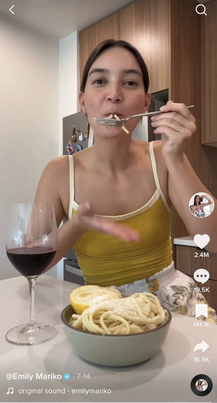 Emily eating pasta with a glass of red wine on the table