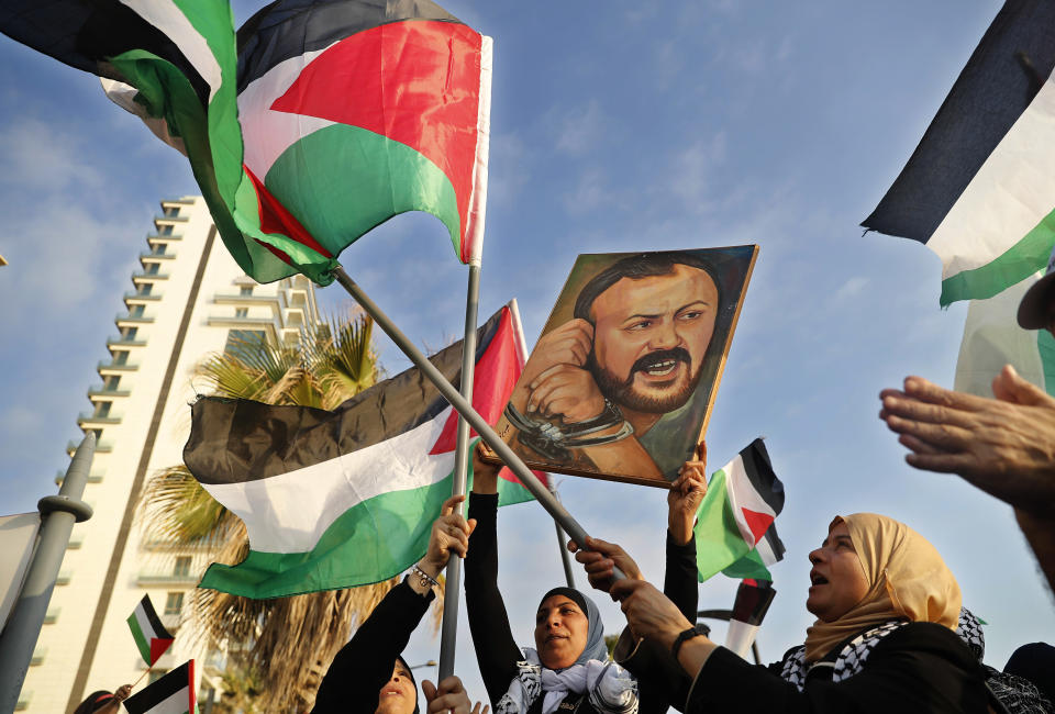 FILE - Palestinian women shout slogans while waving their national flags with a picture of jailed leader Marwan Barghouti, during a protest in Beirut, Lebanon, on May 4, 2017. Hamas officials say that any cease-fire deal with Israel should include the release of prisoner Marwan Barghouti — a leader of the militant group's main political rival. The demand by Hamas marks the central role Barghouti plays in Palestinian politics — even after more than two decades behind bars and sentenced by Israel to multiple life terms in prison. (AP Photo/Hussein Malla, File)