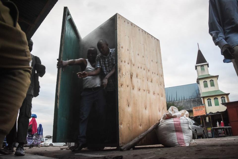 Men leave the steam inhalation booth installed by Tanzanian herbalist Msafiri Mjema in Dar es Salaam, Tanzania.