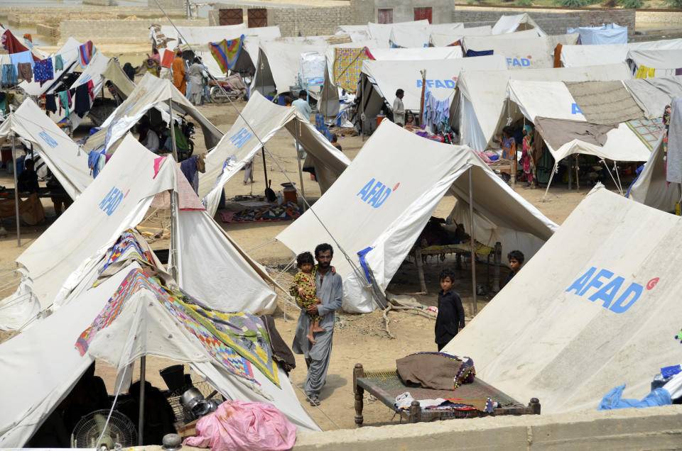 Families take a refuge at a camp after leaving their flood-hit homes, in Jaffarabad, a district of Baluchistan province, Pakistan, Wednesday, Sept. 21, 2022. Devastating floods in Pakistan's worst-hit province have killed 10 more people in the past day, including four children, officials said Wednesday as the U.N. children's agency renewed its appeal for $39 million to help the most vulnerable flood victims. (AP Photo/Zahid Hussain)