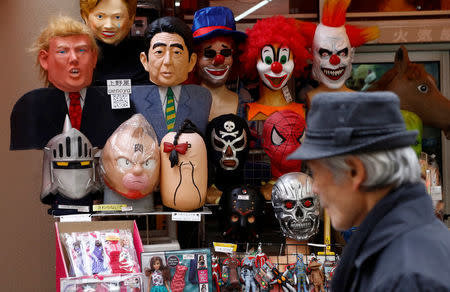 A man walks past a shop selling masks of U.S. President Donald Trump (L top) and Japanese Prime Minister Shinzo Abe at a market street in Tokyo, Japan January 23, 2017. REUTERS/Kim Kyung-Hoon