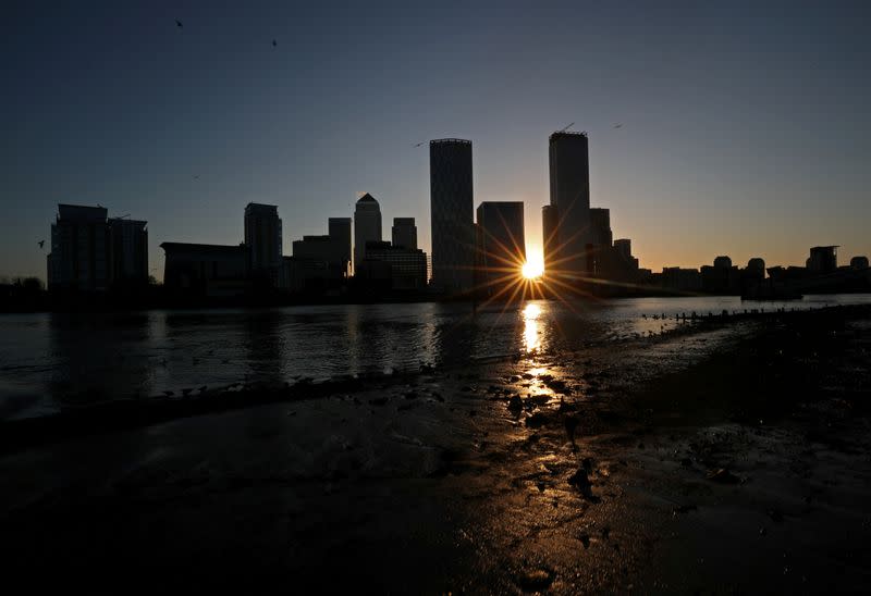 FILE PHOTO: The sun rises behind the Canary Wharf financial district in London
