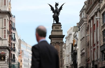 FILE PHOTO: A pedestrian walks past a City of London dragon boundary marker in London, Britain, September 23, 2015. REUTERS/Suzanne Plunkett/File Photo