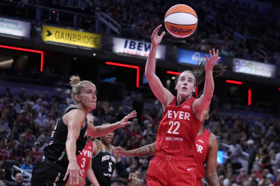 Indiana Fever's Caitlin Clark (22) grabs a rebound ahead of New York Liberty's Leonie Fiebich (13) during the first half of a WNBA basketball game, Saturday, July 6, 2024, in Indianapolis. (AP Photo/Darron Cummings)