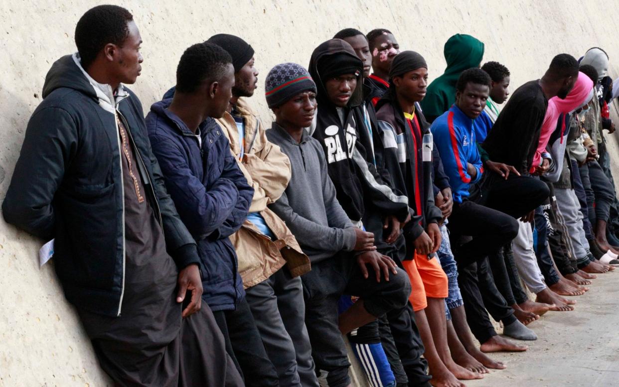 Migrants line up after being brought to shore  in Garaboli by a Libyan coast guard from the Mediterranean Sea