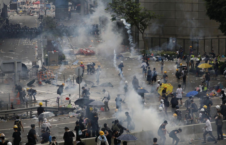 FILE - In this file photo taken Wednesday, June 12, 2019, riot police try to disperse protesters with fire tear gas outside the Legislative Council in Hong Kong. Hong Kong police have resorted to harsher-than-usual tactics to suppress protesters this week in the city’s most violent turmoil in decades. Police fired rubber bullets and beanbag rounds at the crowds, weapons that have not been widely used in recent history. (AP Photo/Vincent Yu, File)