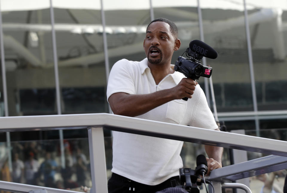 US actor Will Smith holds a camera prior to the start of the Emirates Formula One Grand Prix at the Yas Marina racetrack in Abu Dhabi, United Arab Emirates, Sunday, Nov. 25, 2018.(AP Photo/Luca Bruno)
