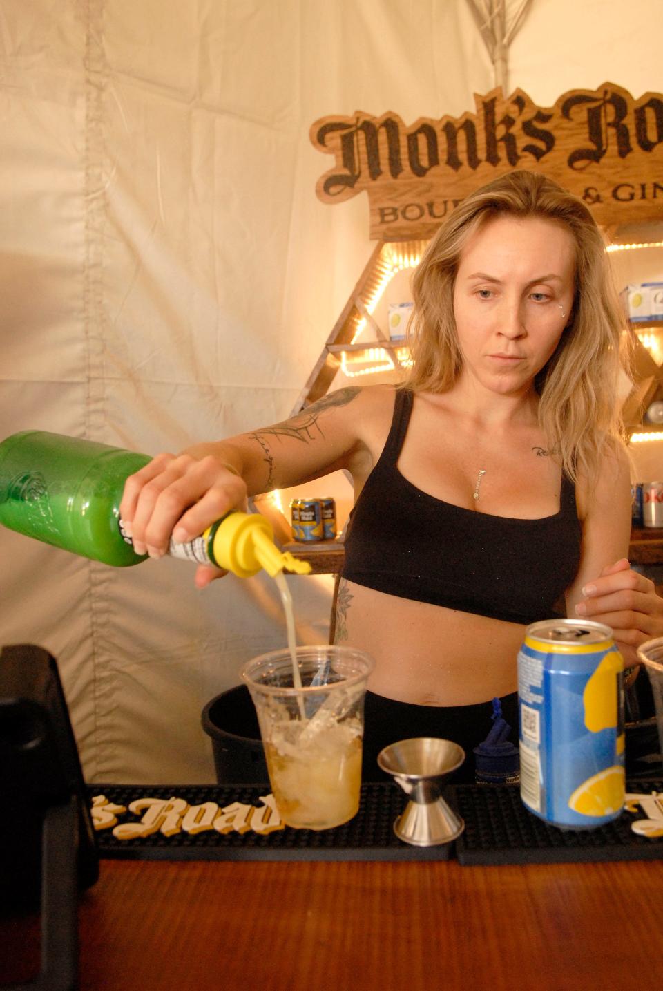 Ashley Jaggers makes a “Goldrush” cocktail at the Log Still distillery booth at Louder Than Life on Saturday. Sept. 23, 2023