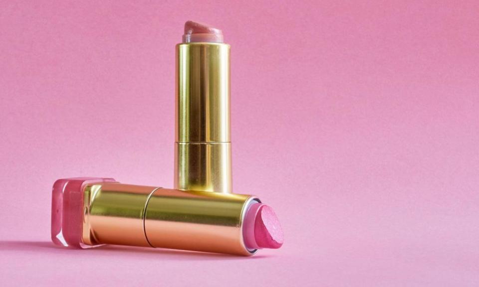 nearly empty lipstick tubes on a pink background