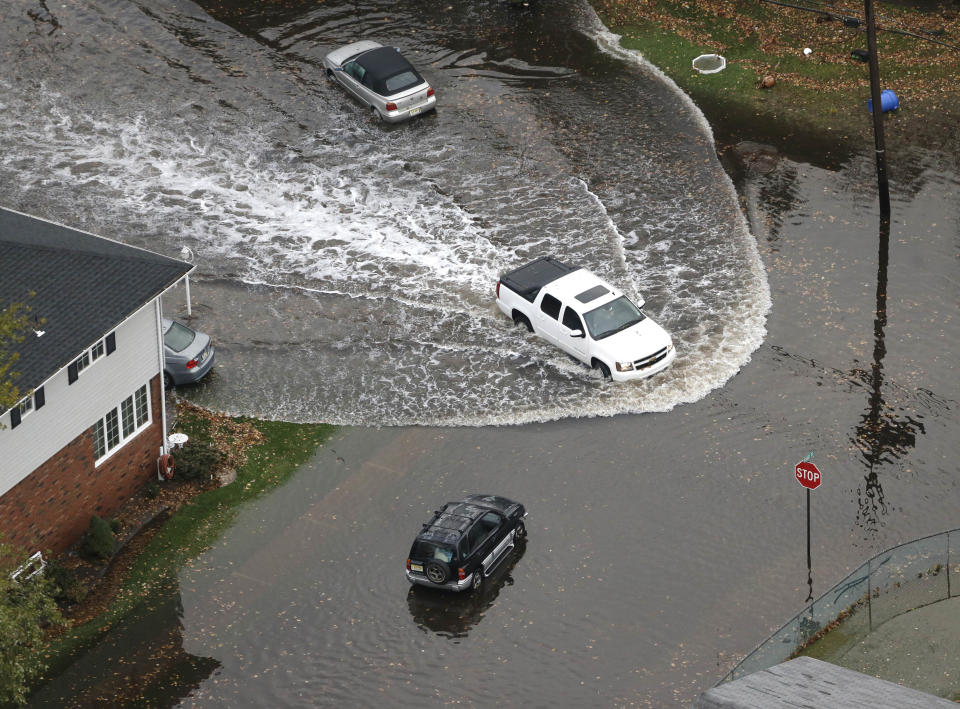 A vehicle drives on a flooded street in the wake of superstorm Sandy on Tuesday, Oct. 30, 2012, in Little Ferry, N.J. Sandy, the storm that made landfall Monday, caused multiple fatalities, halted mass transit and cut power to more than 6 million homes and businesses. (AP Photo/Mike Groll)
