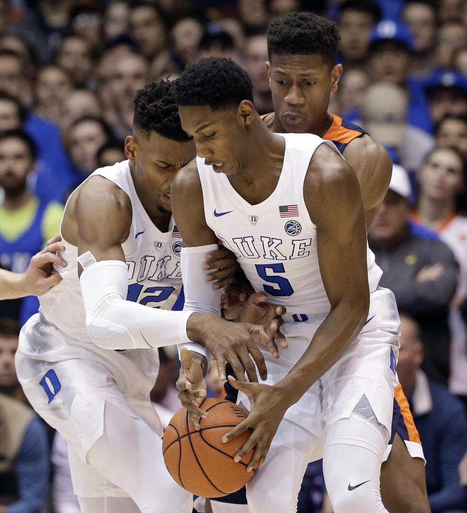 Duke's Javin DeLaurier (12) and RJ Barrett (5) struggle for possession of the ball with Virginia's De'Andre Hunter, rear, during the first half of an NCAA college basketball game in Durham, N.C., Saturday, Jan. 19, 2019. (AP Photo/Gerry Broome)