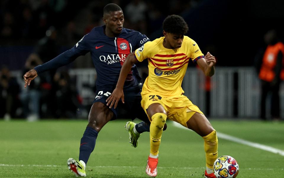 Barcelona's Spanish forward #27 Lamine Yamal (R) and Paris Saint-Germain's Portuguese defender #25 Nuno Mendes