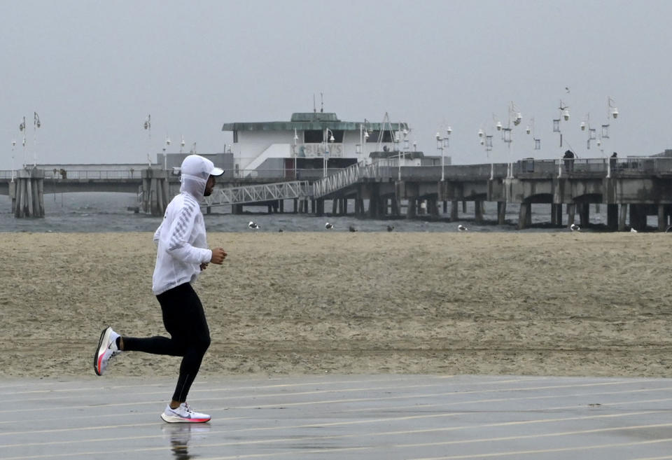 Wet weather is no barrier for joggers along the bike path in Long Beach, Calif., on Monday, Oct 25, 2021. (Brittany Murray/The Orange County Register via AP)