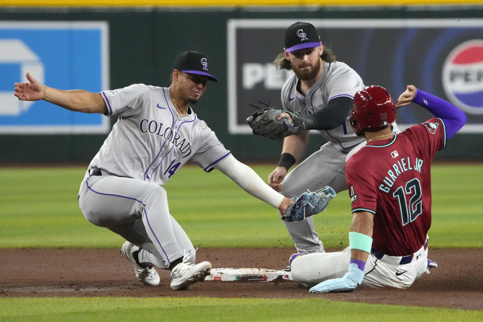 Arizona Diamondbacks' Lourdes Gurriel Jr. steals second base between Colorado Rockies shortstop Ezequiel Tovar (14) and second baseman Brendan Rodgers during the first inning during a baseball game, Sunday, March 31, 2024, in Phoenix. (AP Photo/Rick Scuteri)