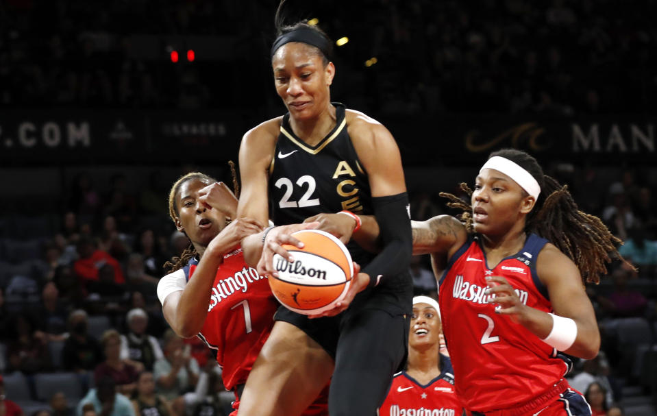 Las Vegas Aces forward A'ja Wilson (22) pulls down a rebound between Washington Mystics guard Ariel Atkins (7) and forward Myisha Hines-Allen (2) during the first half of a WNBA basketball game Thursday, Aug. 31, 2023, in Las Vegas. (Steve Marcus/Las Vegas Sun via AP)