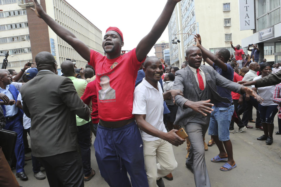 Opposition party suppoters sing and dance while waiting to hear a speech by the country's top opposition leader in Harare, Wednesday, Nov. 20, 2019. Zimbabwean police with riot gear fired tear gas and struck people who had gathered at the opposition party headquarters to hear a speech by the main opposition leader Nelson Chamisa who still disputes his narrow loss to Zimbabwean President Emmerson Mnangagwa. (AP Photo/Tsvangirayi Mukwazhi)