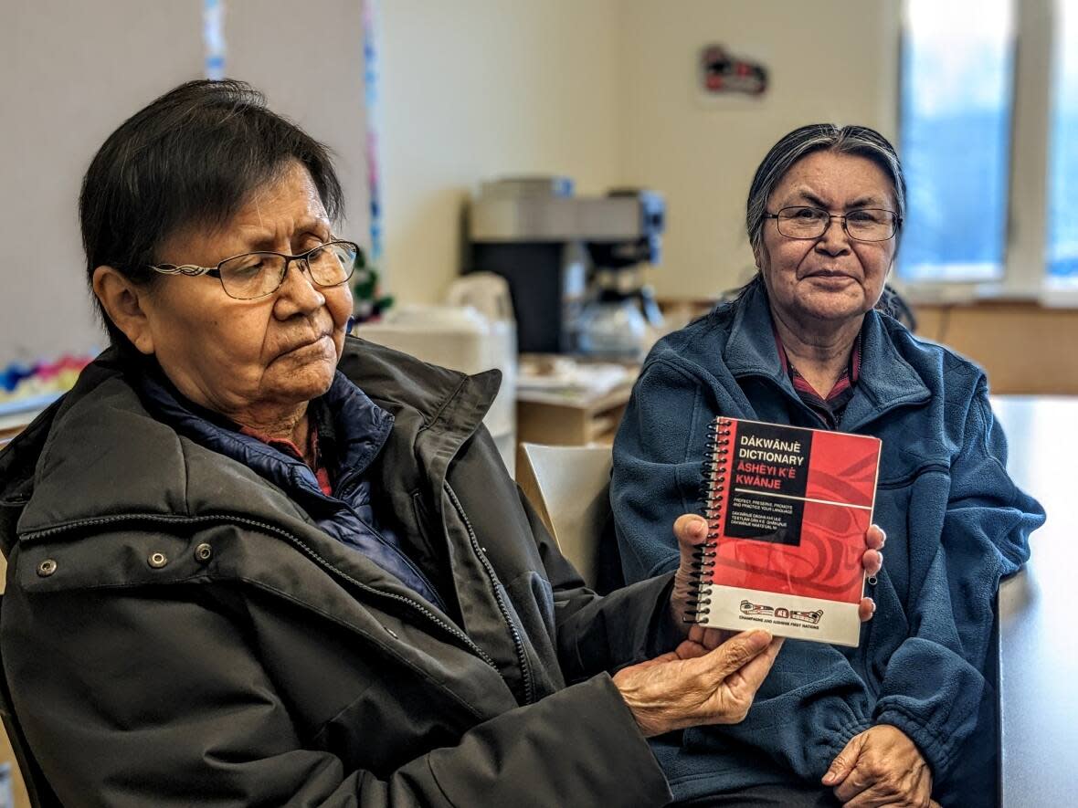 Lena Smith-Tutin and her sister Vivian Smith hold their Southern Tutchone dictionary at the Da Kų Cultural Centre in Haines Junction, Yukon. The sisters spent 7 years collecting basic and essential words to create the dictionary.  (Virginie Ann / CBC News - image credit)