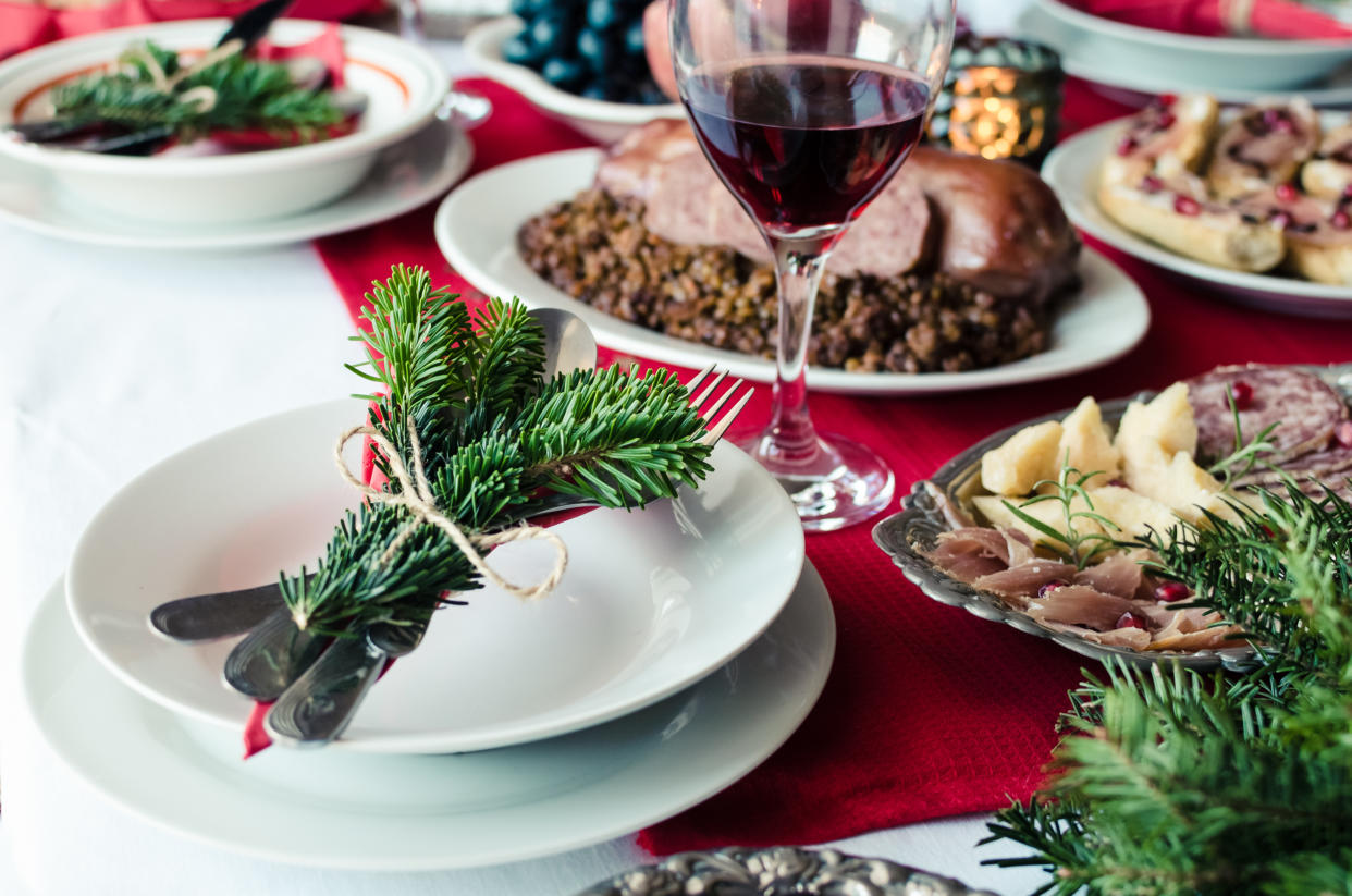 Family together Christmas celebration concept. Festive place setting for holiday dinner with natural decorations from fir tree branches.