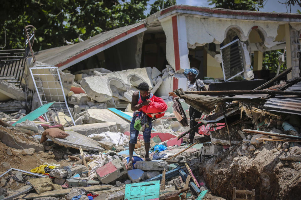 Locals recover their belongings from their homes destroyed in the earthquake in Camp-Perrin, Les Cayes, Haiti, Sunday, Aug. 15, 2021. The death toll from the magnitude 7.2 earthquake in Haiti soared on Sunday as rescuers raced to find survivors amid the rubble ahead of a potential deluge from an approaching tropical storm. (AP Photo/Joseph Odelyn)