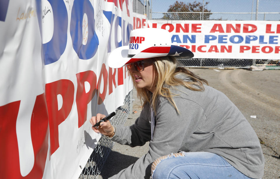Melanie Ramey of Tupelo, writes a personal message of support on a banner supporting President Donald Trump, outside the BancorpSouth Arena in Tupelo, Miss., Friday, Nov. 1, 2019, before a Keep America Great Rally. (AP Photo/Rogelio V. Solis)