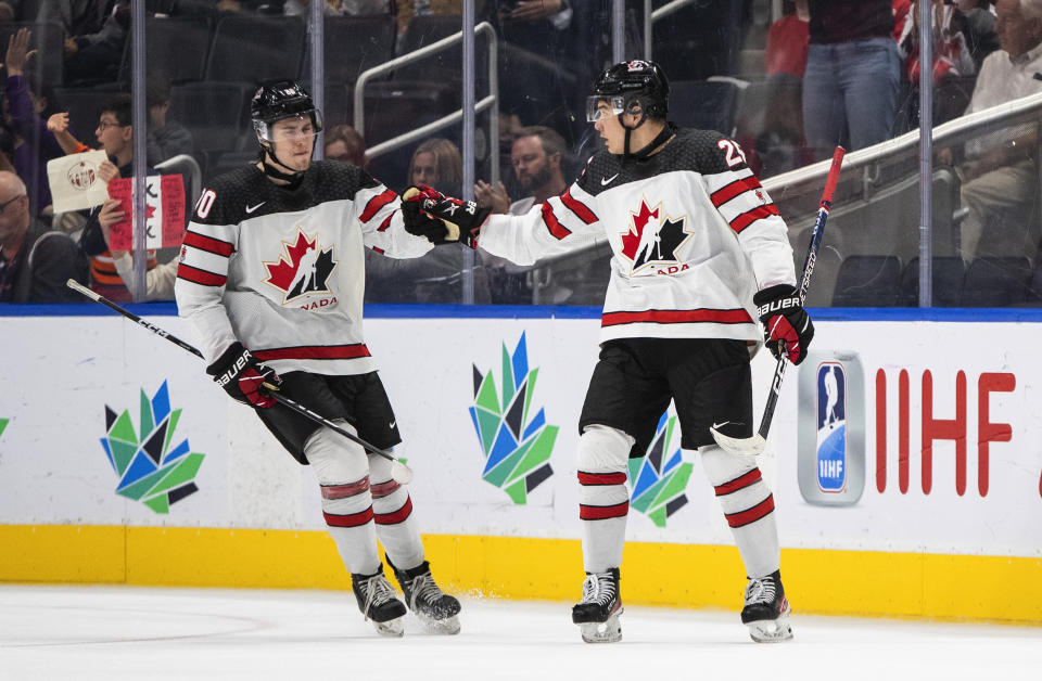 Canada's Zack Ostapchuk (20) and William Dufour (25) celebrate a goal against Latvia during the third period of an IIHF junior world hockey championships game Wednesday, Aug. 10, 2022, in Edmonton, Alberta. (Jason Franson/The Canadian Press)