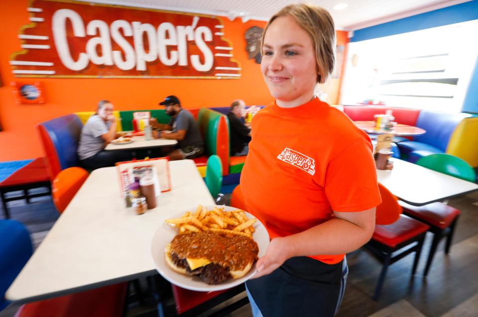 Casper's employee Addy Crocker carries a chili cheeseburger to a table at Casper's on Tuesday, July 11, 2023.