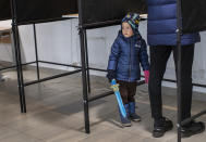 A child looks out of booth at a polling station during the second round of a parliamentary election in Vilnius, Lithuania, Sunday, Oct. 25, 2020. Polls opened Sunday for the run-off of national election in Lithuania, where the vote is expected to bring about a change of government following the first round, held on Oct. 11, which gave the three opposition, center-right parties a combined lead. (AP Photo/Mindaugas Kulbis)