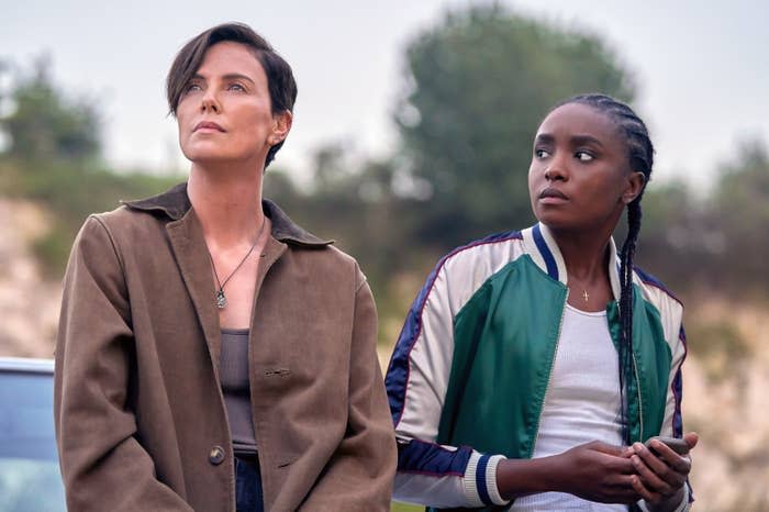 Charlize Theron and KiKi Layne wearing casual clothing, standing outdoors with serious expressions, possibly in a scene from a movie or TV show