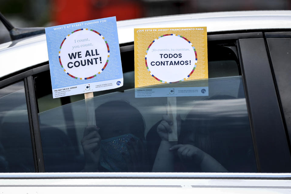 Two young children hold signs through the car window that make reference to the 2020 U.S. Census, at an outreach event in Dallas on 25, 2020. (Tony Gutierrez / AP file)