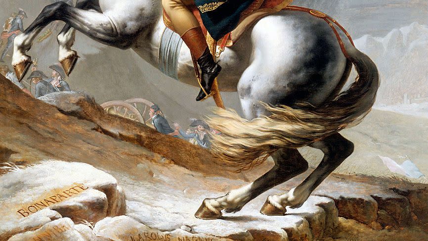 napoleon rides a bucking horse and points on finger in the air, he wears a military uniform including a hat and red cape