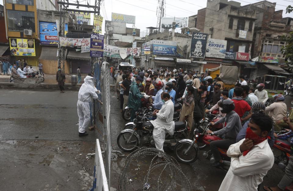 FILE - In this Thursday, June 25, 2020 file photo, police officers stop motorcyclists from entering a restricted area that is sealed off to control the spread of the coronavirus, in Lahore, Pakistan. For months, experts have warned of a potential nightmare scenario: After overwhelming health systems in some of the world's wealthiest regions, the coronavirus gains a foothold in poor or war-torn countries ill-equipped to contain it and sweeps through the population. (AP Photo/K.M. Chaudhry, File)