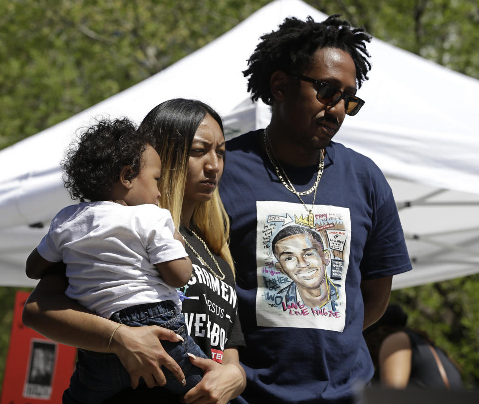 FILE - In this March 31, 2018 file photo Salena Manni, the fiancee of police shooting victim Stephon Clark, holds the couple's son, Aiden as she and Clark's uncle, Curtis Gordon attend a rally aimed at ensuring Clark's memory and calling for police reform, in Sacramento, Calif. Two Sacramento police officers won't face criminal charges for the fatal shooting of Clark following a chase that ended in his grandparents' yard and started a series of angry protests that roiled California's capital city, the county's top prosecutor announced Saturday, March 2, 2019, following a nearly yearlong investigation. (AP Photo/Rich Pedroncelli,File)